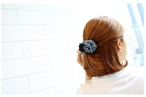 Detailed view of a blue fabric flower hair claw clip worn by a model from the side