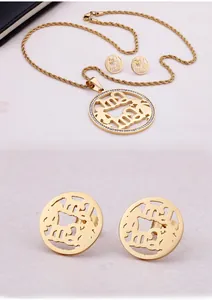 Close-up detail of golden Mama pendant and matching stud earrings with zircon stones