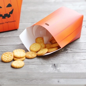Creative orange Halloween pumpkin gift box filled with cookies on a rustic wood surface