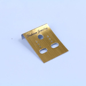 Detailed view of golden plastic earring display card with brushed texture and black text