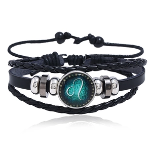 Detailed view of layered leather bracelet featuring a glowing Leo constellation glass charm