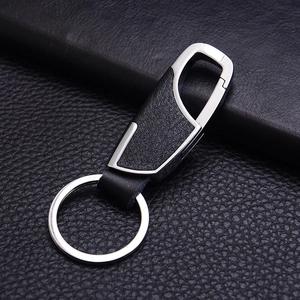 Creative silver metal and black faux leather car keychain displayed on a leather background