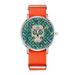 Detail of a minimalist silver watch with orange nylon strap and sugar skull pattern dial
