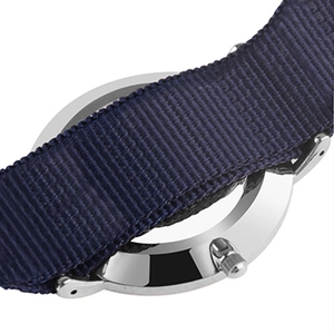 Close-up of silver metal watch case back with dark blue nylon strap and crown detail