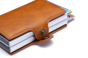 Detail view of brown PU leather card holder with aluminum pop-up card mechanism and snap button