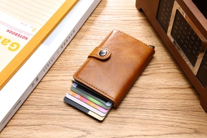 Brown leather wallet with aluminum card holder showing tiered cards on wooden desk