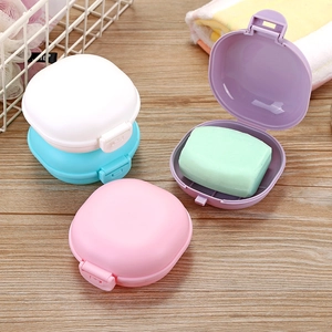 Portable travel soap dish with lid in multiple colors on a wooden table setup