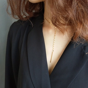 Detail of thin gold 925 sterling silver chain necklace with vertical bar pendant on model