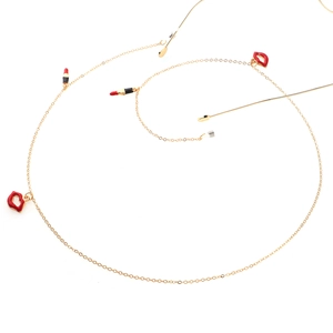 Golden eyewear chain with red lip and lipstick charms on a clean white background