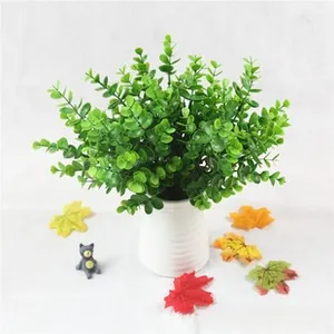 Detailed view of artificial eucalyptus leaves in a white ceramic vase on a cloth background