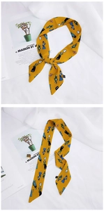 Detailed view of a yellow cartoon silk scarf tied in a bow and laid flat for styling