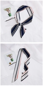 Detail of a striped skinny silk scarf in navy blue, pink and white on a magazine