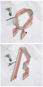 Detail of narrow silk scarf featuring pink stripes and white polka dots on beige