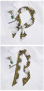 Detail of skinny silk scarf with yellow geometric stripes and floral pattern tied as a bow