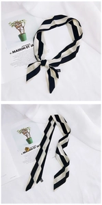 Detailed view of striped silk scarf knotted and draped on a lifestyle magazine background