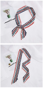 Detail view of a long silk scarf with red and blue geometric arrow patterns on white fabric