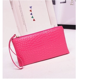 Detail of fuchsia crocodile pattern wristlet bag with zipper and golden hardware