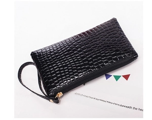 Detail of black crocodile texture wristlet with golden zipper and leather strap