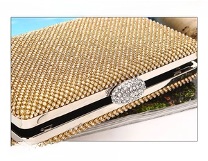 Detailed close-up of handmade gold evening clutch with sparkling rhinestones and metal clasp