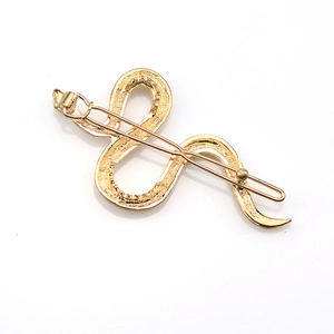 Macro shot of gold-toned snake-shaped hair clip showing detailed metal texture and design