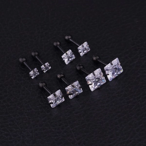 Macro detail of four pairs of black square zircon stud earrings on textured black leather
