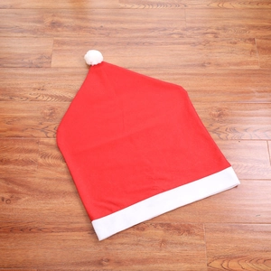Red Christmas hat chair cover with white pompom and plush trim on wooden floor