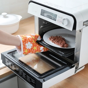 Orange heat-resistant oven mitt with floral pattern used for taking tray out of the oven