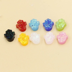 Top view of colorful resin Hamsa hand charms with sparkling glitter texture for DIY jewelry