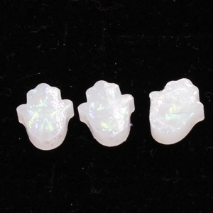 Detailed macro view of three white opal Hamsa hand charms on a black velvet surface