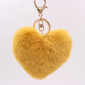 Detail of soft yellow heart-shaped plush keychain with gold metal clasp on white background