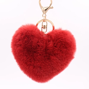 Macro view of red heart plush keychain featuring soft faux fur and golden metal clasp