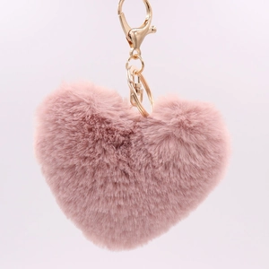 Detail of pink heart-shaped plush keychain with a soft faux fur texture and gold metal clip