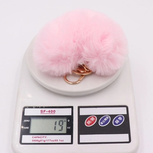 Pink plush heart keychain with gold ring on scale showing lightweight 19g weight
