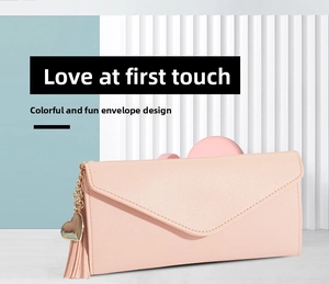 Detail of pink long wallet with envelope design, golden heart pendant and tassel
