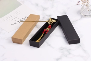 Detailed view of an elegant gold butterfly hairpin with red beads in a black gift box