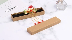 Traditional gold hairpin with red floral charm inside a brown kraft jewelry gift box