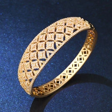Macro shot of gold-plated bangle featuring intricate lattice hollow pattern and pavé zircons