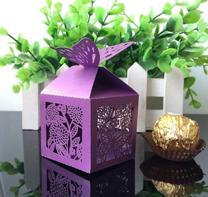 Detail of laser-cut ivory butterfly favor box with intricate floral hollow pattern