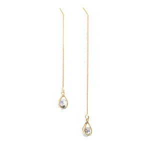 Boucles d'oreilles pendantes dorées avec zircons en goutte d'eau sur fond blanc épuré