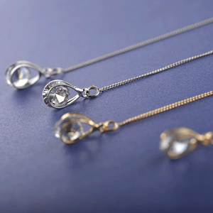 Vue macro des pendentifs goutte en zircon doré et argenté avec chaînes délicates
