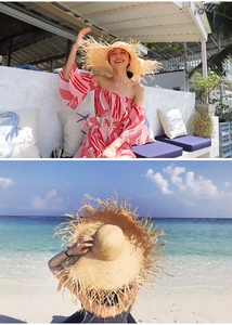 Detailed view of oversized straw sun hat with frayed edges and red striped resort dress