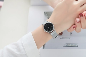 Minimalist silver mesh strap quartz watch with black dial worn on a female wrist