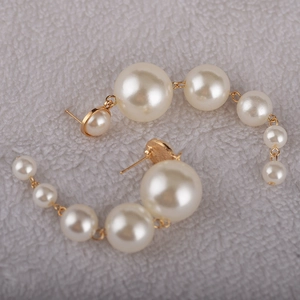Close-up of elegant gold earrings featuring a cascading row of white baroque pearls