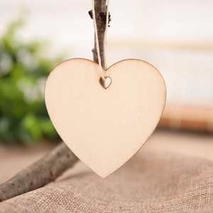 Macro detail of heart-shaped wooden Christmas ornaments hanging on a branch with jute rope