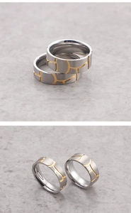 Close-up of silver titanium steel couple rings with gold geometric engravings