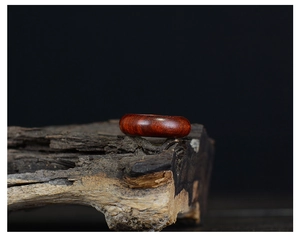 Polished redwood ring displayed on natural tree bark background with zen lighting