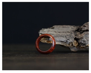 Close-up of deep red-brown wooden ring with natural grain on weathered wood