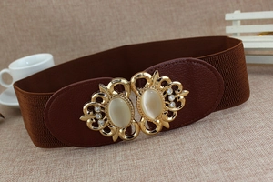Detail of a brown elastic waist belt featuring a gold floral buckle and cream gemstones