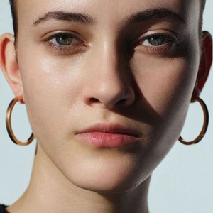 Close-up of large gold hoop earrings on model highlighting sleek metallic shine