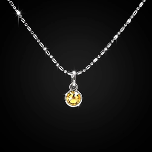 Close-up of a silver beaded necklace featuring a faceted yellow crystal pendant on black